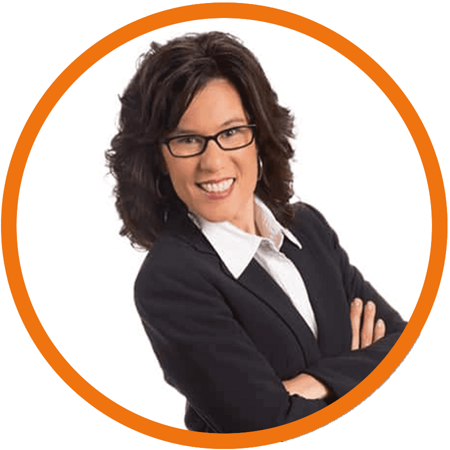 A woman with curly dark hair and glasses stands smiling.